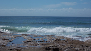 Person standing rocky beach surfboard - a surfboard free wallpaper