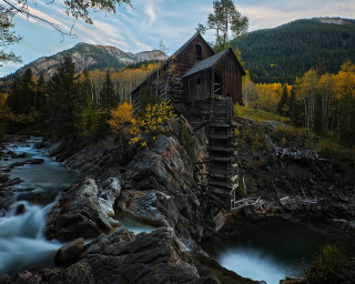 Wooden building rocky hillside river - yellow leaf free wallpaper
