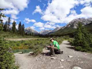 Man sitting rock river mountains - a backpack free wallpaper
