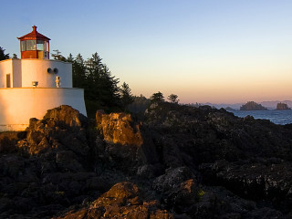 Lighthouse rocky cliff ocean sunset 4 - a boat in the distance free wallpaper