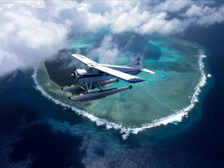 Plane flying small island ocean - ecological art free wallpaper