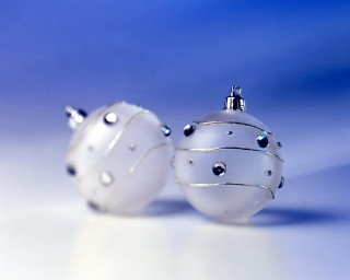 Two white ornaments sitting on 3 - a table together free wallpaper