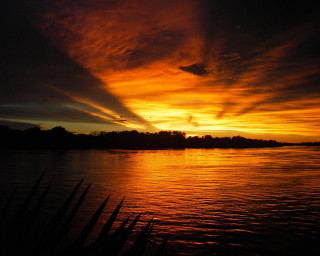 Sunset water sky clouds trees - a sunset over a body of water free wallpaper