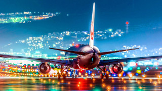 Jetliner night runway city lights - side and a city in the background free wallpaper