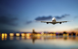 Plane flying water night city - over a body of water free wallpaper